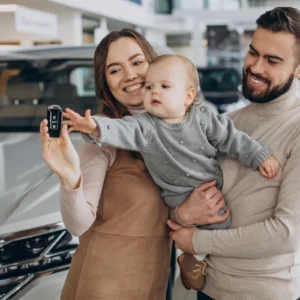 Família feliz segurando chave de carro novo em concessionária, ilustrando um artigo da BKOpen sobre quanto custa um seguro de carro.