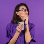 Mulher pensativa segurando smartphone em fundo roxo, ilustrando um artigo da BK Open sobre bancos tradicionais.